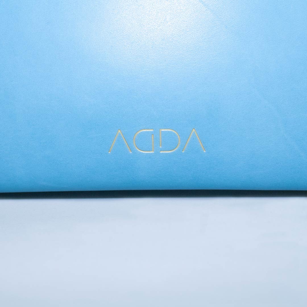Logoprägung von AGDA auf azurblauem vegetabil gegerbtem Leder.