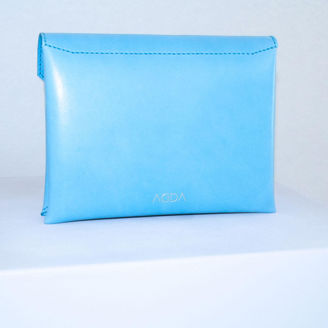 Rückansicht von blauer kleiner Handtasche mit goldenem Logo.