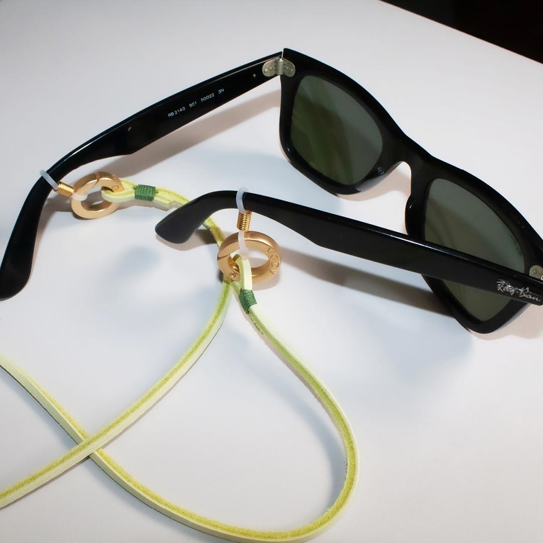 Brillenband an einer schwarzen Sonnenbrille. Premium Lederband mit Metallhalterungen von AGDA.